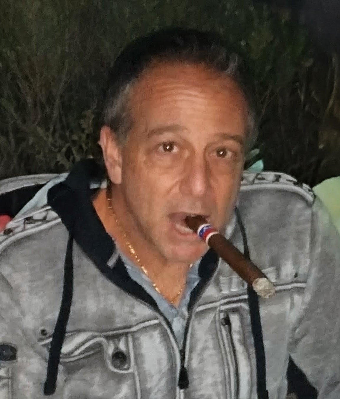 Tony Lawand with a cigar in a grey hoodie
